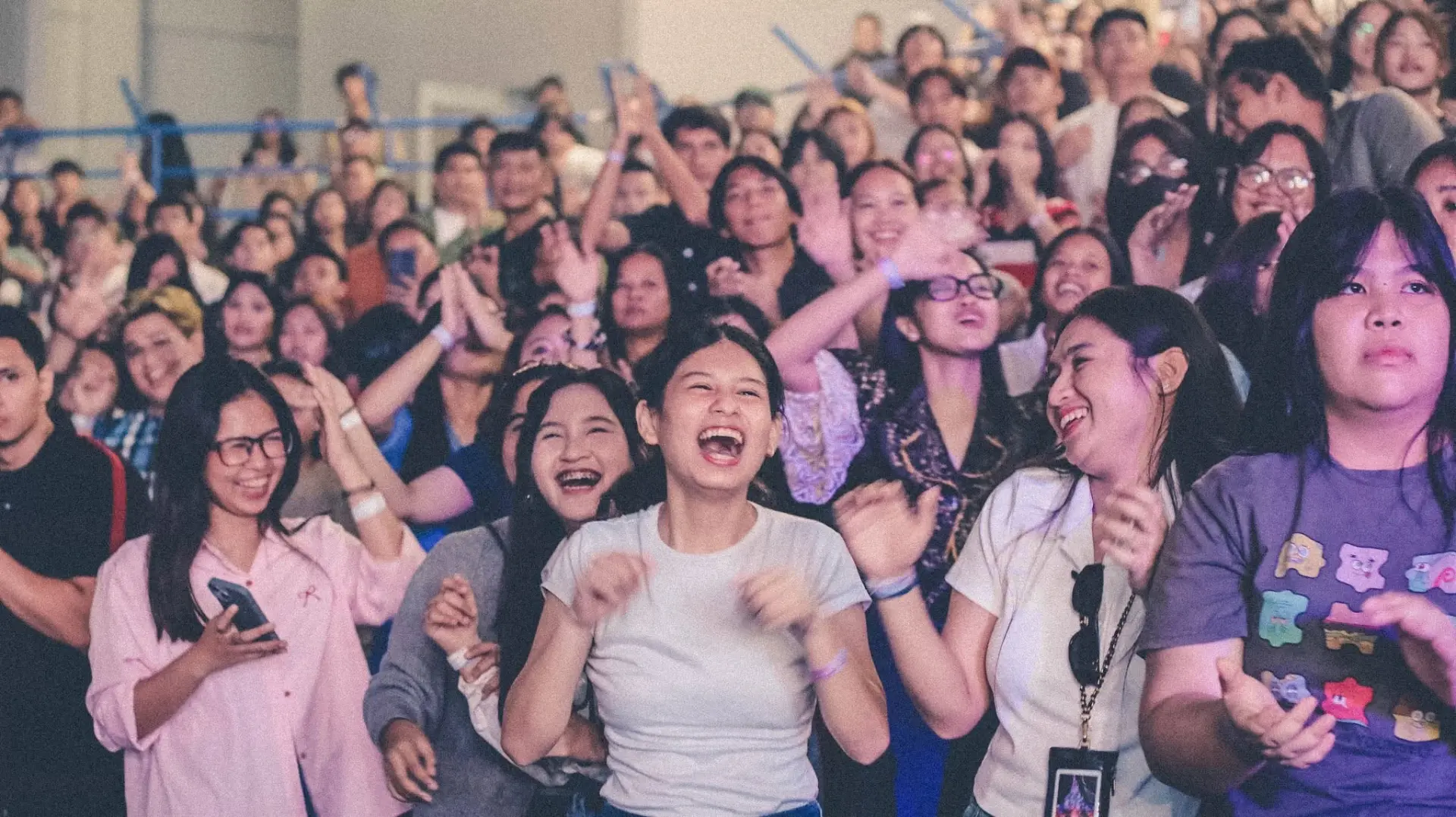 A crowd of young people cheering and clapping in stadium seating